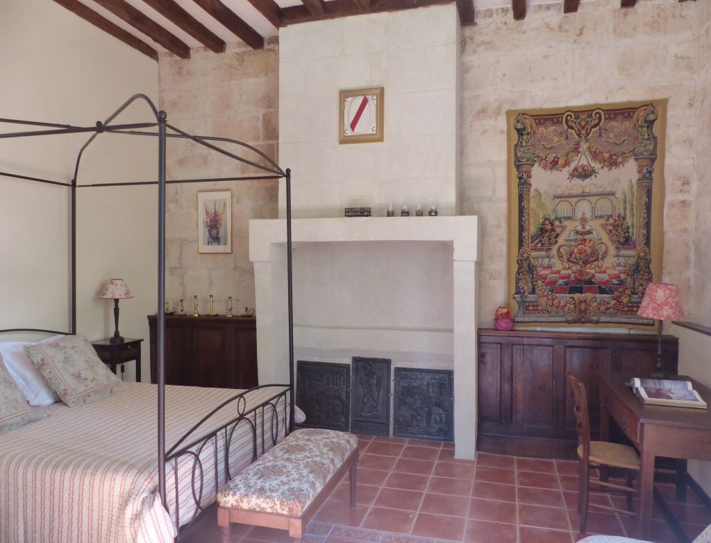 chambre avec un lit, cheminée et mur en pierre